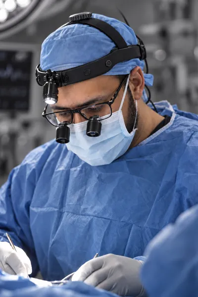 Dr. Padela operating, wearing surgical loupes and a headlight